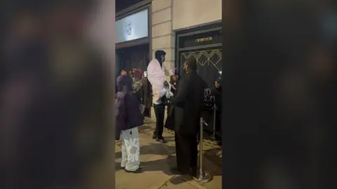 A man sits on the shoulders of another man to appear taller. 