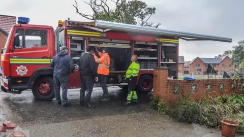 Norfolk Fire Museum A 1990s Mercedes fire engine. Four men are standing next to it, and two of them are wearing hi-vis jackets.