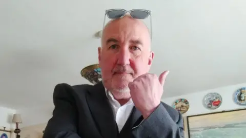 Barry Von Clemens Barry Von Clemens is pictured in a living room. He is bald, with sunglasses pushed back over his head, and has a short, white goatee beard. He wears an open-necked white shirt and a dark jacket.