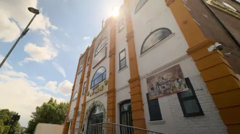 An imposing gathering  of 3  storeys, with pick  bricks and six bladed  terracotta bricked sections.