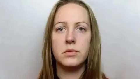 The Cheshire Police is a detention photo of Lucy Latbi, who has a longer golden hair and wearing a red top.