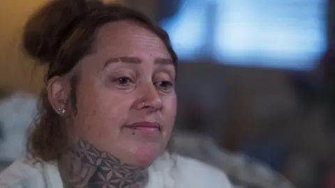 BBC Crimewatch Live Head and shoulders shot of Danielle Reynolds sitting on a sofa with tied up brown hair and wearing a white top