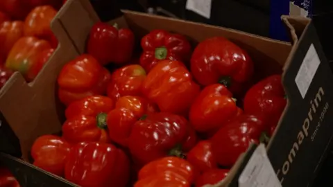 Andy Meeson/BBC A cardboard box of fresh red peppers, propped up at an angle, with the peppers catching the light.