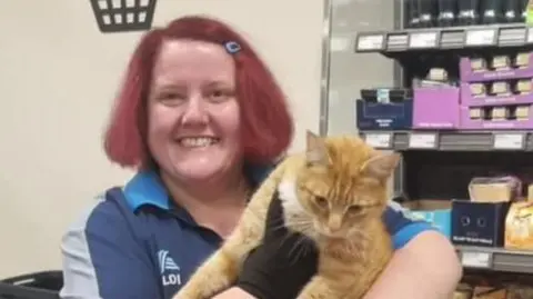 Raymond the ginger cat with Aldi shop worker Lara Milne