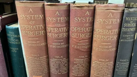 Ollie Conopo/BBC A row of old medical books, including four volumes of A System of Operative Surgery.