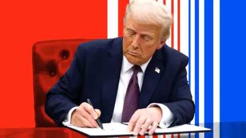 Donald Trump wearing dark suit and red tie signing an executive order at his desk. In the background here are red and blue bright stripes.