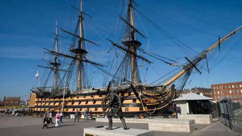 Getty Images HMS Victory at Portsmouth Historic Dockyard with people walking around.