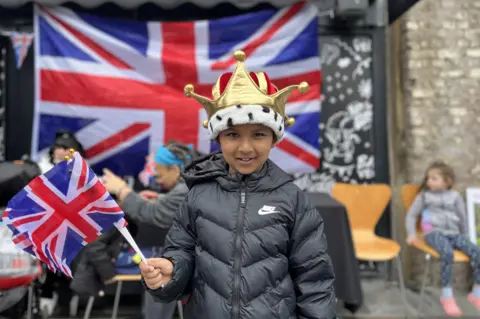 BBC The child of a volunteer waives a flag in his crown