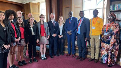 Students and JCG staff stand on one side and on the other side is the High Commissioner and headteachers from Rwanda