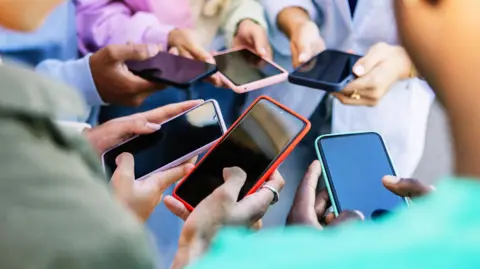 A group of young people hold smartphones in a circle 