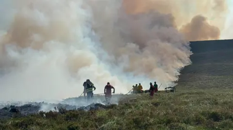 several people beating down smoking grass on a hillside