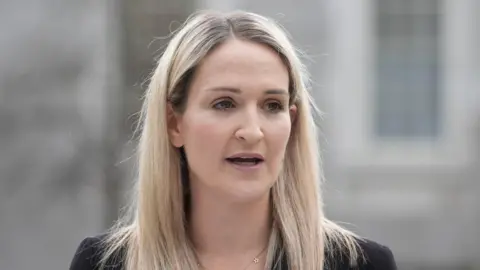 PA Media Helen McEntee, a woman with blonde hair. She is pictured from the shoulders up. The background of the image is blurred. 