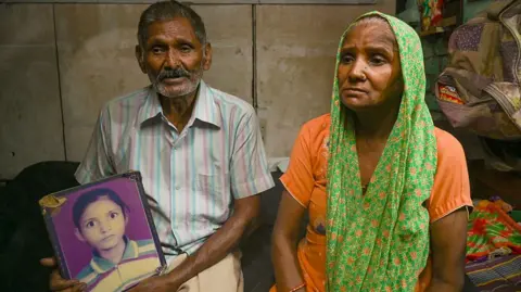  the victim of Nithari case, looking at the picture of his daughter Jyoti in his home in Nithari on July 30, 2025 in Noida, India. The Supreme Court has rejected a total of 14 appeals filed against the acquittal of Surendra Koli, accused in the much-talked-about Nithari case of 2006. Moninder Singh Pandher and his domestic help Koli were accused of raping and murdering their neighbours, especially children, in Nithari, Uttar Pradesh. Koli was awarded death penalty by the trial court on September 28, 2010. The high court acquitted Pandher and Koli of the death penalty, holding that the prosecution failed to prove their guilt 'beyond reasonable doubt' and calling it a 'botched' investigation. (Photo by Sunil Ghosh/Hindustan Times via Getty Images)
