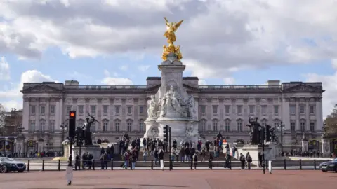Getty Images General view of the front of Buckingham Palace and the Victoria Memorial with a crowd of people on the steps in front.