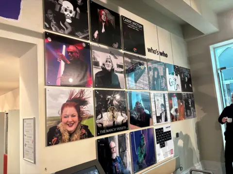 Jack Conlon/BBC A wall featuring rows of pictures, some showing people. Next to the pictures are the words 'who's who'.