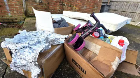 Paul Moseley/BBC A pile of fly-tipped junk, including a table, two mattresses, a small child's bike, cardboard boxes and foil.