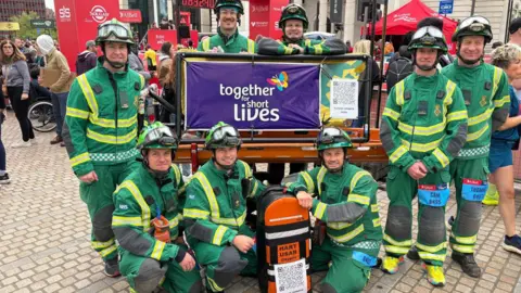 Great Birmingham Run The crew from West Midlands Ambulance Service that ran the race. They are wearing full uniform of green and yellow and standing next to the stretcher they carried as they ran.
