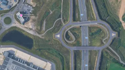 A satellite picture shows the M49 roundabout junction without any vehicles on. It also shows a missing connecting road between the junction and a nearby industrial estate