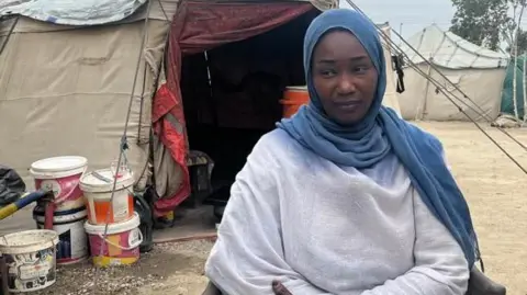 Hanna sits in front of a tent in a disposal camp in Port Sudan.