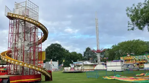 A helter skelter slide and various fair rides can be seen on Platt Fields Park.
