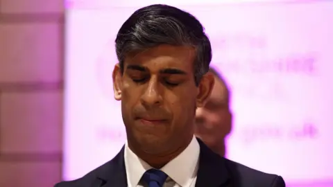 PA Media A grim-faced Rishi Sunak looks down at an election count in Northallerton.
