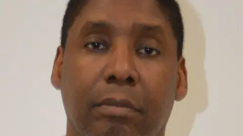 Metropolitan Police Oghenochuko Ojiri mugshot. He is staring directly at the camera. He has brown hair and brown eyes.