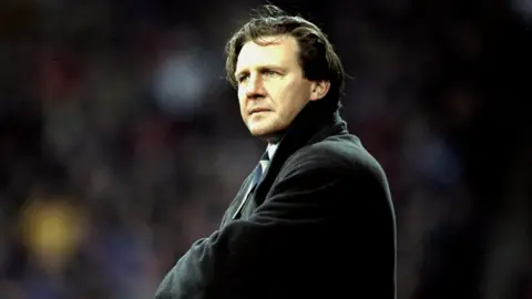 Getty Images Football manager Peter Jackson, pictured with wavy brown hair and a black coat. He appears to be stood on a touchline at a football match.