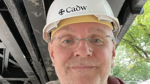 CADW Jonathan Berry, senior inspector with Cadw, the Welsh government's archaeological service looks straight at the camera wearing a hard hat.