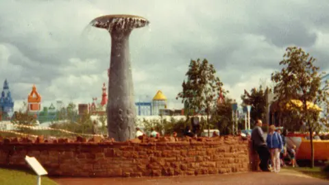 The Children of Glasgow fountain at the Garden Festival in 1988 - it is a large grey fountain surrounded by a red brick wall
