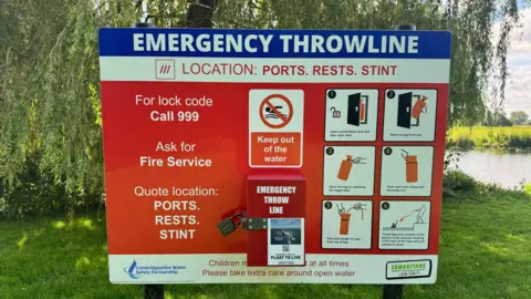 A red sign board with information on keeping out of the water and instructions for a throw line.