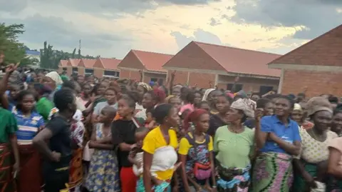A large crowd of people in front of some red-brick buildings