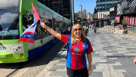 Amanda, wearing a club t-shirt, waves a Crystal Palace flag