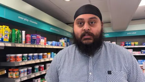 Pharmacist Manpreet Gill in front of shelves in the store