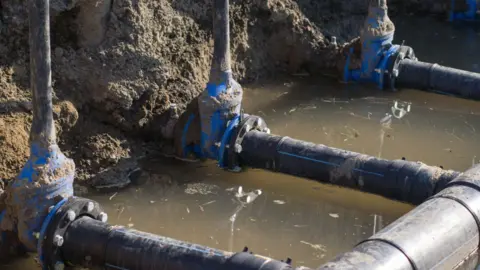 Getty Images Three water mains with water running underneath