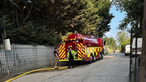 Don Gregory Two firefighters by a fire engine near Fowles Skip Hire.