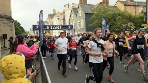 Dozens of people running through the starting posts of the run. 