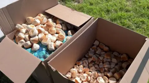 Two cardboard boxes side by side with small golden bread rolls inside them.