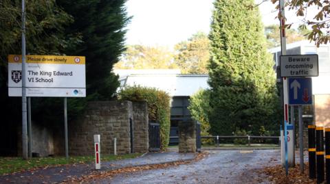 The road into a school with a sign The King Edward V1 school on the right