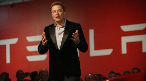 Elon Musk in suit talks to crowd at Tesla event