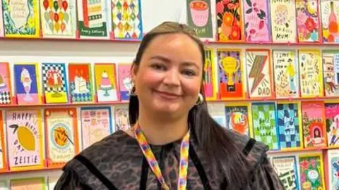 Kerrie McNeill standing in tradeshow booth with colourful cards.