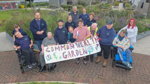 Gordon Terris Workers and people who use Parklea;s facilities standing in front of the Saltire garden, on display in a new location