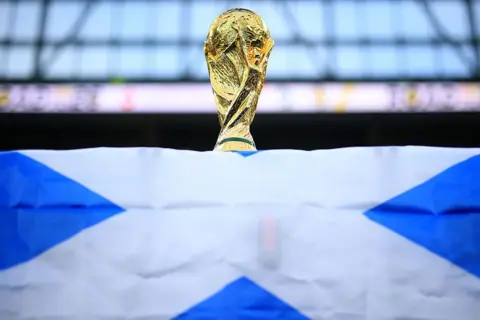 A World Cup trophy is perched on top of a Scotland flag.