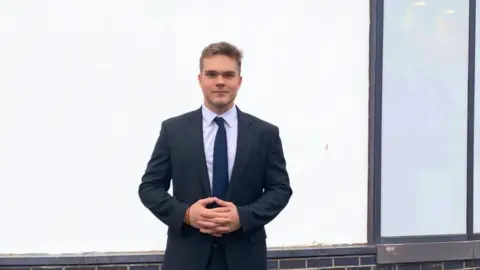 Westbourne School, Penarth Illia in a dark suit standing outside his school.