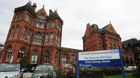 PA Media The exterior of Leeds General Infirmary, with reddish-brown bricks and cars parked outside