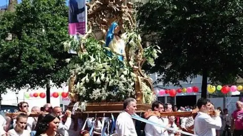 Paul Burnell/BBC Members of Manchester Italian Association carry a flower laden statue of the Virgin Mary in the annual Manchester procession