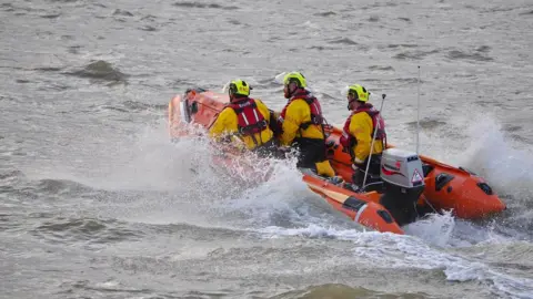 Stranraer RNLI A lifeboat crew speeding out to see with foam spraying up from beside their orange lifeboat