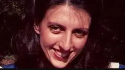 A woman with long dark hair against a dark background