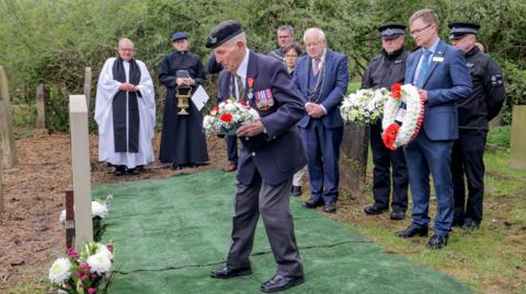 Veteran Ken Cooke lays a wreath at Rober Smith's grave surrounded by well-wishers