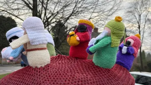 Jules Harper-Orne Knitted figures on a postbox in Wolverhampton include the three wise men bearing gifts and a figure carrying a baby at the front, representing Mary, Joseph and Jesus.