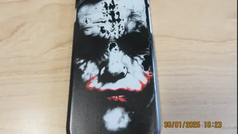 Cheshire Police An iPhone device with a cover depicting the face of the Joker villain from the Batman franchise, which has its face smeared in white make-up and red lipstick. 